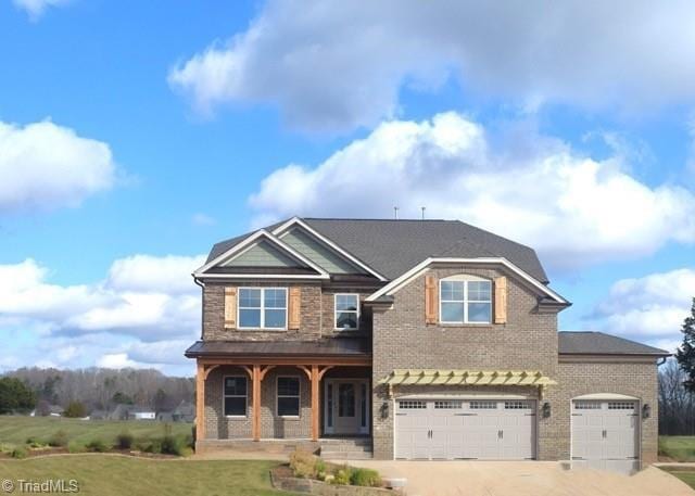 8128 Simon Dr Lot 49, Stokesdale, NC 27357 - craftsman inspired home with covered porch, driveway, brick siding, an attached garage, and a front lawn