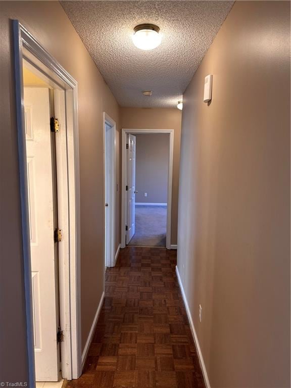 hall featuring dark parquet flooring and a textured ceiling