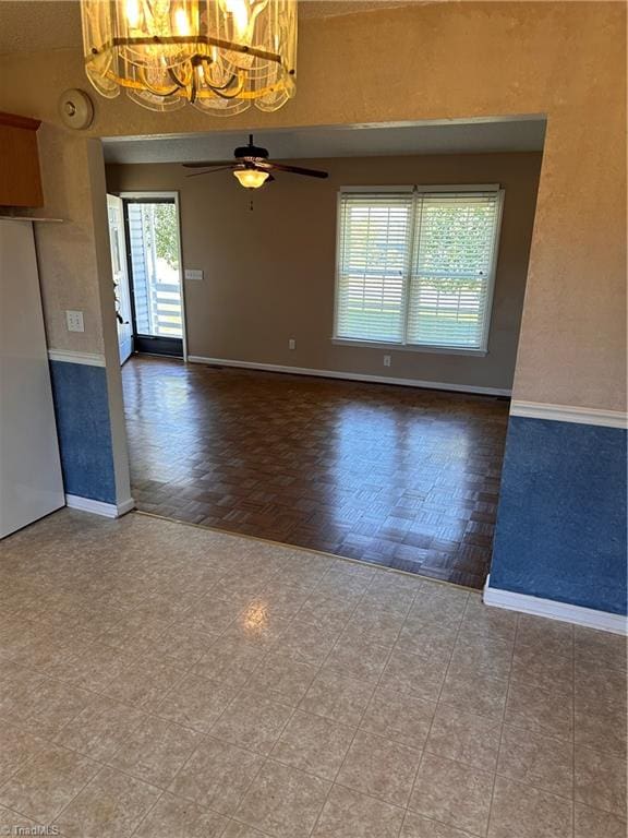 interior space featuring parquet flooring, ceiling fan with notable chandelier, and a wealth of natural light