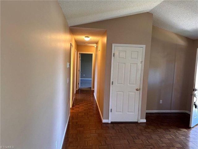 hall with dark parquet floors, a textured ceiling, and vaulted ceiling