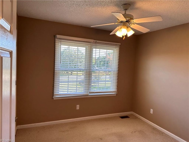 carpeted empty room with ceiling fan and a textured ceiling