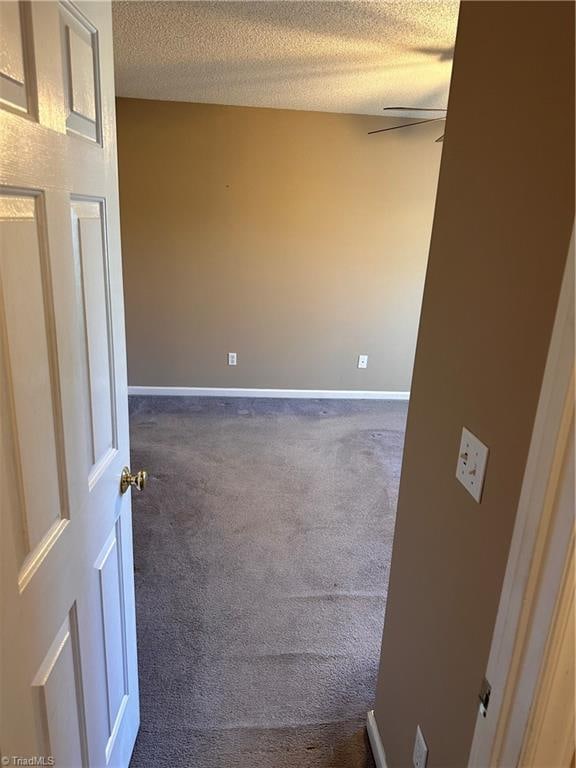 unfurnished room featuring a textured ceiling and dark colored carpet