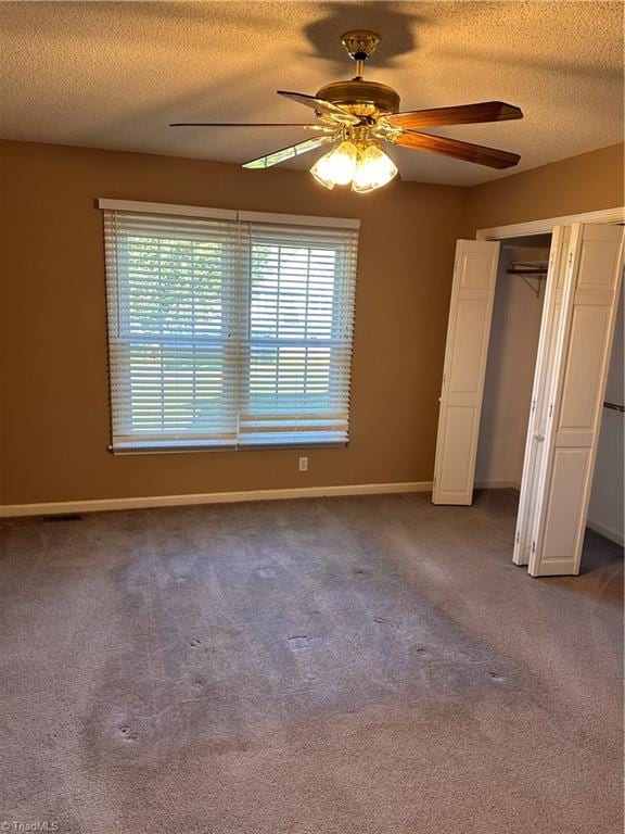 unfurnished bedroom with a closet, a textured ceiling, carpet floors, and ceiling fan