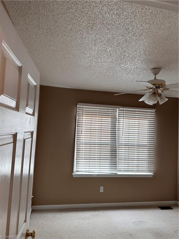 carpeted empty room with a textured ceiling and ceiling fan