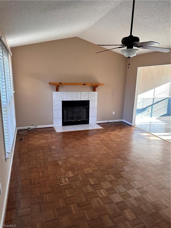 unfurnished living room featuring a tile fireplace, lofted ceiling, a textured ceiling, and a wealth of natural light