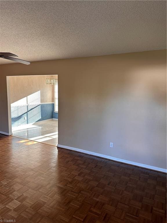 spare room with dark parquet flooring, a textured ceiling, and ceiling fan