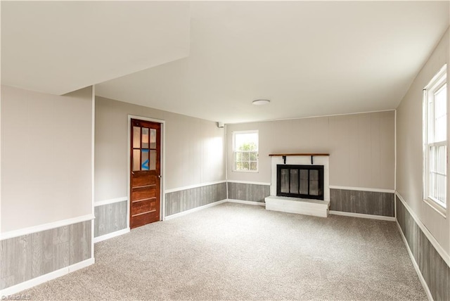 unfurnished living room with carpet flooring and wood walls