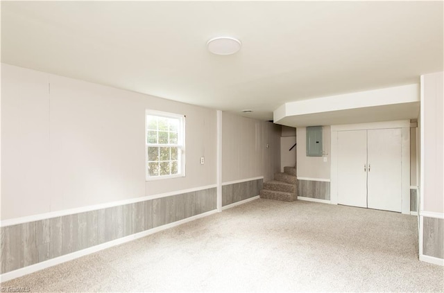 carpeted spare room with electric panel and wooden walls