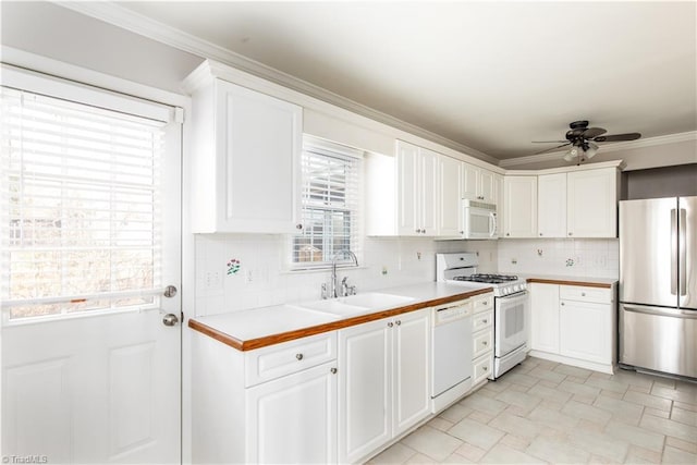 kitchen with a healthy amount of sunlight, white appliances, sink, and white cabinetry