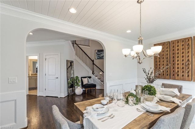 dining space featuring a notable chandelier, ornamental molding, and dark wood-type flooring