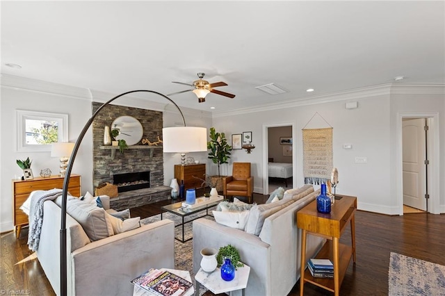 living room with dark hardwood / wood-style floors, a stone fireplace, and crown molding