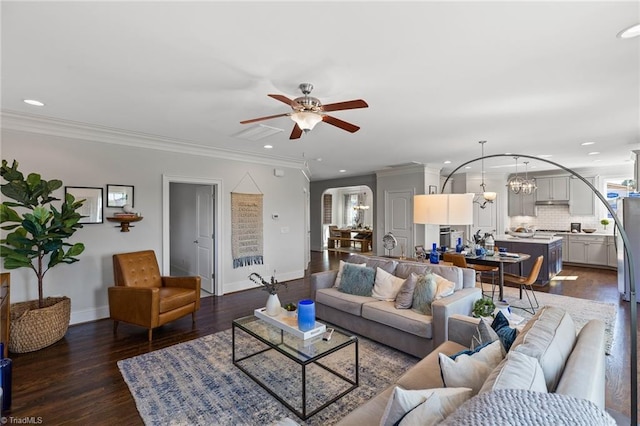 living room with ceiling fan with notable chandelier, dark wood-type flooring, and crown molding