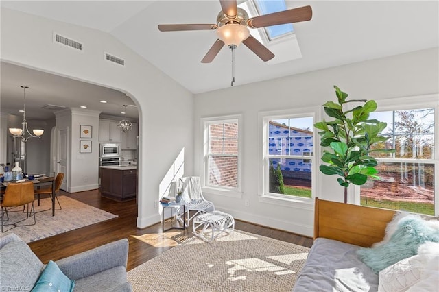 living room with ceiling fan with notable chandelier, dark hardwood / wood-style flooring, vaulted ceiling, and a wealth of natural light