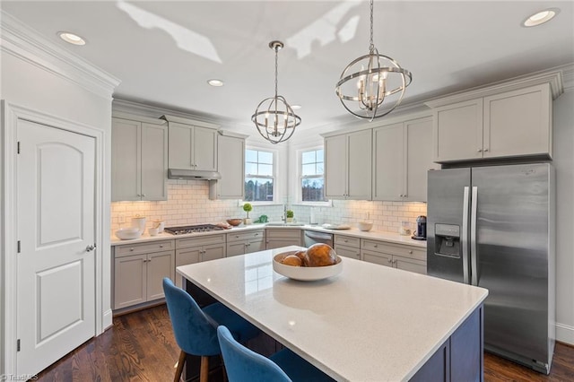 kitchen featuring a center island, stainless steel appliances, a notable chandelier, pendant lighting, and decorative backsplash