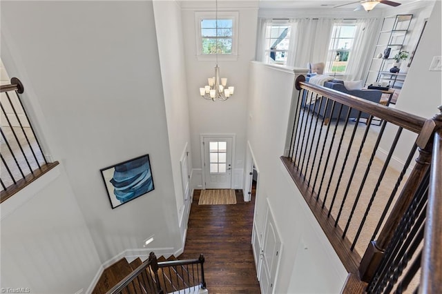 stairway with wood-type flooring and ceiling fan with notable chandelier