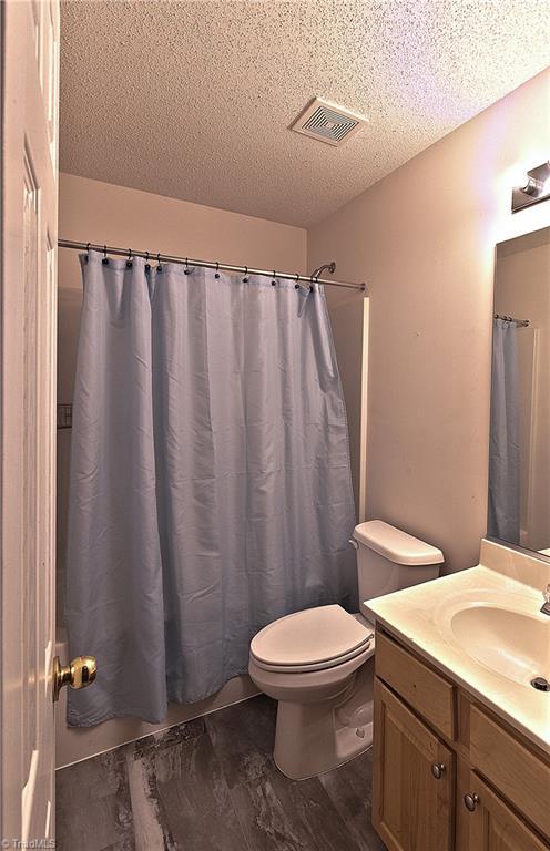 bathroom with a textured ceiling, vanity, hardwood / wood-style flooring, and toilet