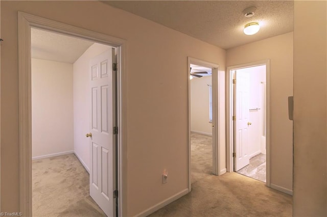 corridor featuring a textured ceiling and light colored carpet