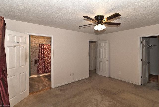 unfurnished bedroom with connected bathroom, ceiling fan, a walk in closet, a closet, and carpet