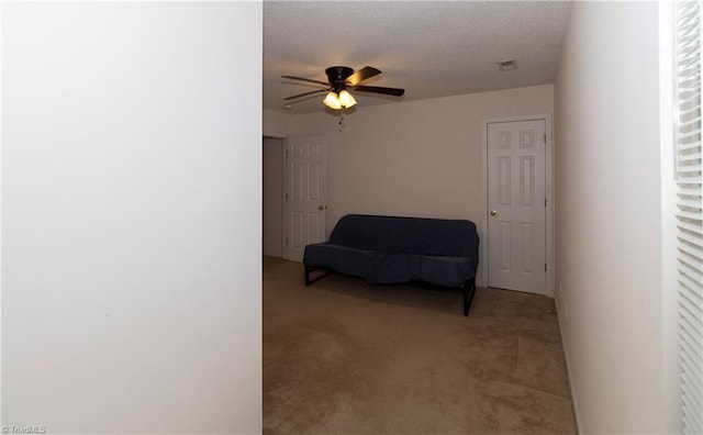 sitting room featuring ceiling fan, light colored carpet, and a textured ceiling