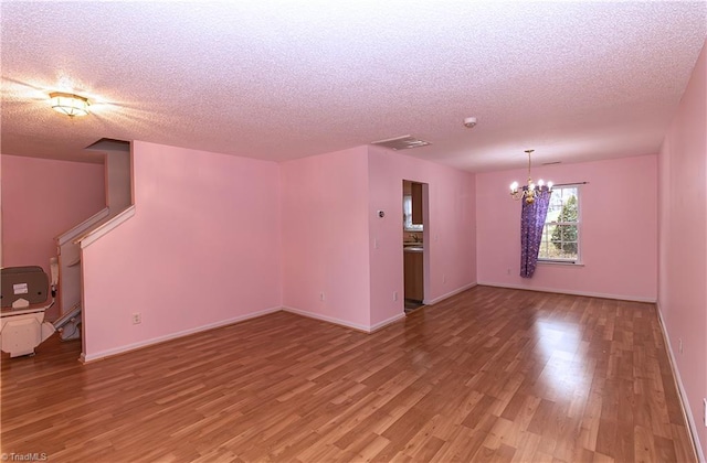 unfurnished living room with wood-type flooring, a textured ceiling, and an inviting chandelier