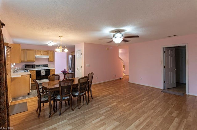 dining room with a textured ceiling, ceiling fan with notable chandelier, light wood-type flooring, and sink