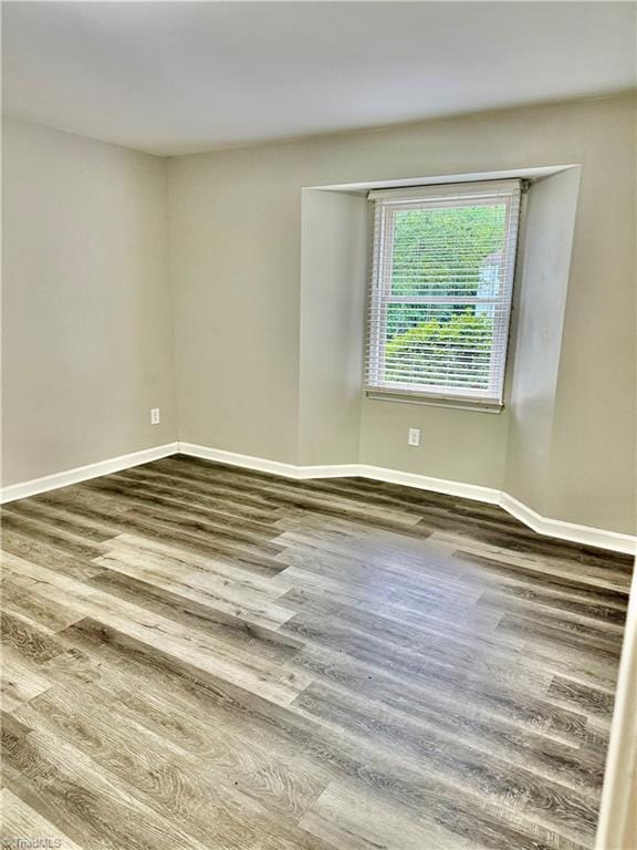 unfurnished room with dark wood-type flooring and baseboards