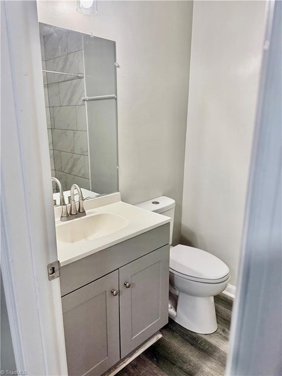 bathroom featuring wood finished floors, toilet, and vanity