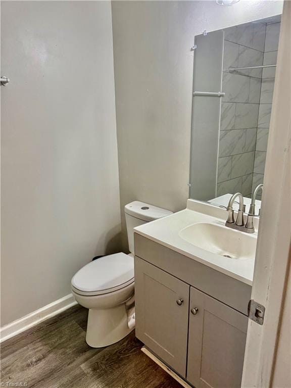 bathroom with wood finished floors, toilet, vanity, and baseboards