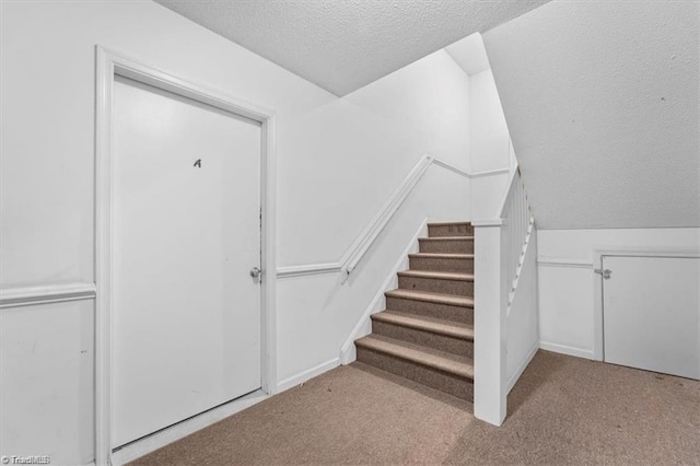 staircase with carpet flooring and a textured ceiling