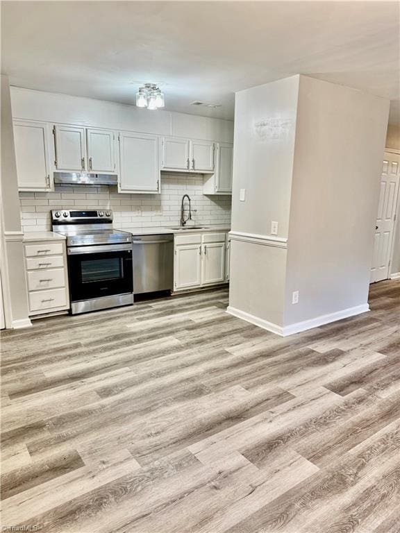 kitchen with stainless steel appliances, under cabinet range hood, light wood-type flooring, tasteful backsplash, and light countertops