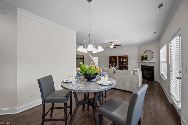 dining area with crown molding, baseboards, dark wood-style floors, a fireplace, and a chandelier
