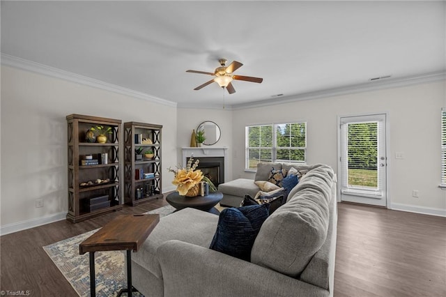 living room featuring ornamental molding, ceiling fan, dark wood-type flooring, baseboards, and a fireplace