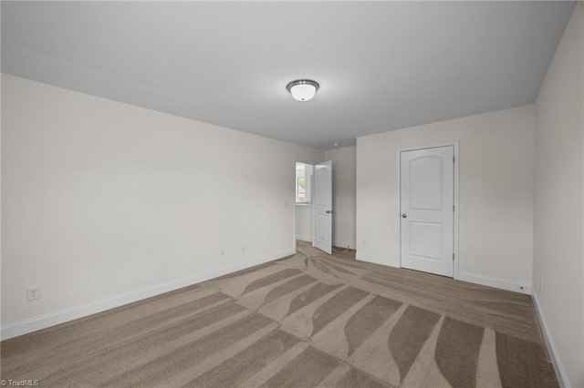 carpeted spare room featuring baseboards