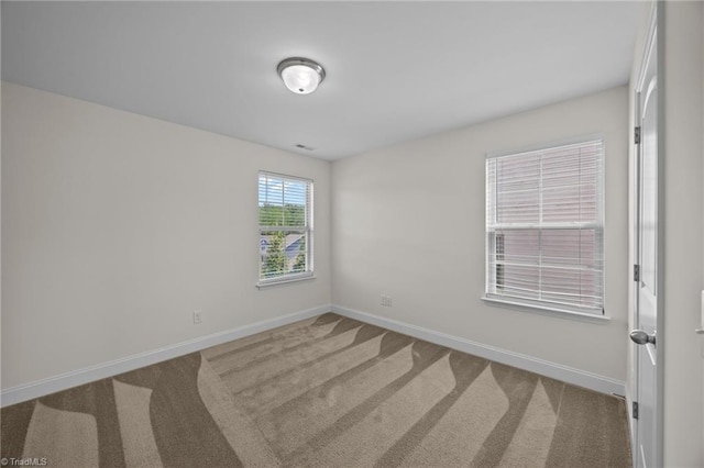 carpeted empty room featuring baseboards