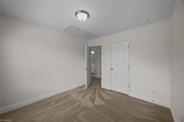 spare room featuring attic access, carpet flooring, baseboards, and a smoke detector