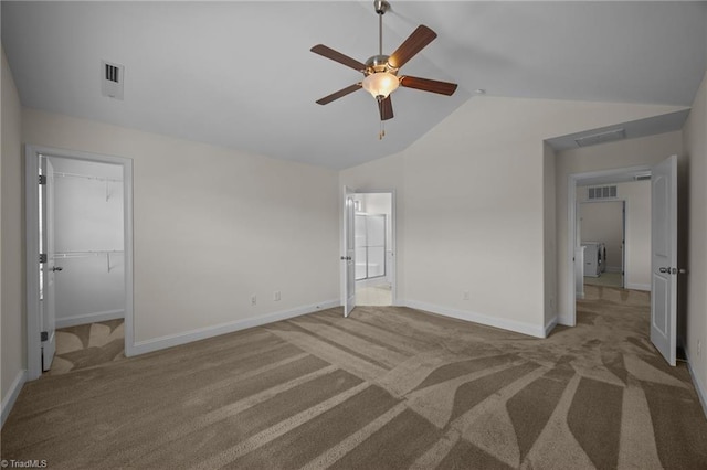 unfurnished bedroom featuring carpet flooring, vaulted ceiling, baseboards, a spacious closet, and a ceiling fan