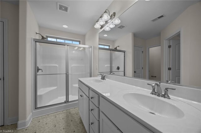 bathroom featuring a shower stall, double vanity, and baseboards