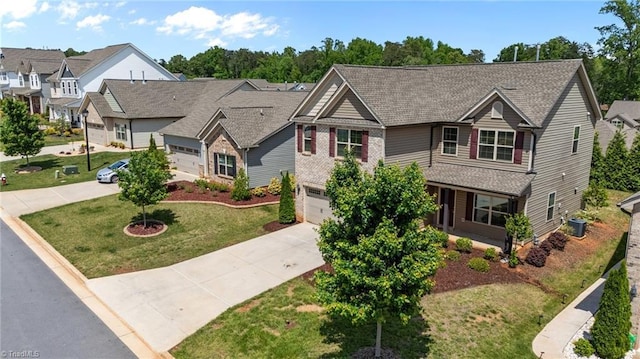 traditional-style home with concrete driveway, a front yard, a residential view, an attached garage, and brick siding