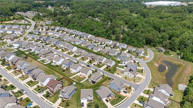 aerial view of property's location featuring nearby suburban area, a forest, and a nearby body of water