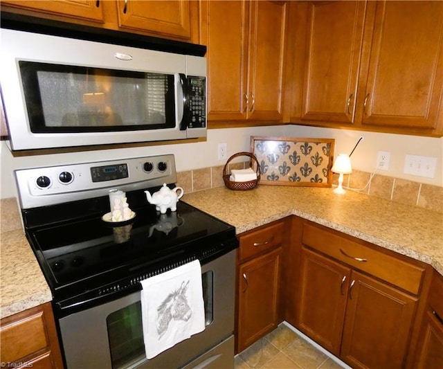 149 Pinewood Ln Unit 104, Bermuda Run, NC 27006 - kitchen featuring stainless steel appliances, brown cabinets, and backsplash