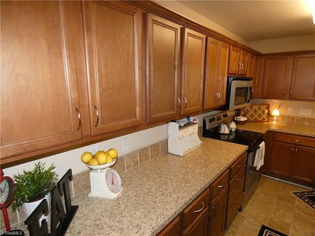 149 Pinewood Ln Unit 104, Bermuda Run, NC 27006 - kitchen with stainless steel appliances, brown cabinetry, and light stone counters