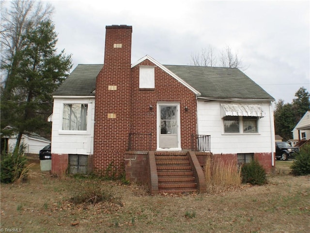 view of front of house featuring roof with shingles and a chimney