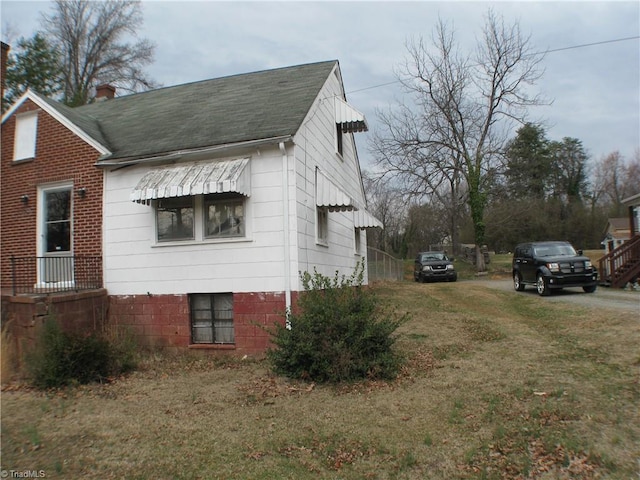 view of home's exterior with a shingled roof and a lawn