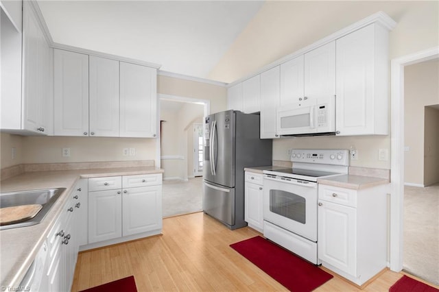 kitchen featuring white cabinetry, sink, vaulted ceiling, light hardwood / wood-style floors, and white appliances