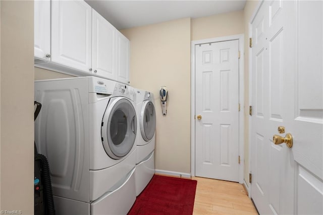 laundry area with cabinets, separate washer and dryer, and light wood-type flooring