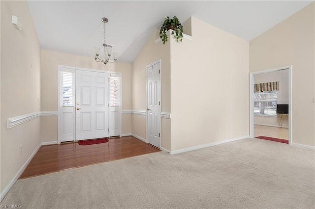 carpeted entrance foyer featuring vaulted ceiling and an inviting chandelier