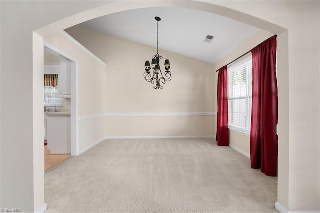 carpeted empty room with sink, lofted ceiling, and an inviting chandelier