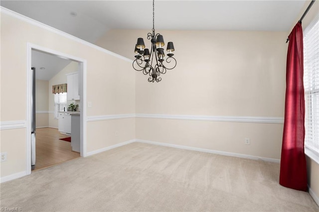 carpeted spare room featuring a notable chandelier, crown molding, and vaulted ceiling