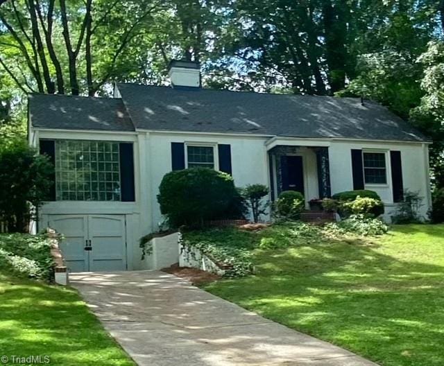 305 W Avondale Dr, Greensboro, NC 27403 - view of front of home with concrete driveway, a garage, a front yard, stucco siding, and a chimney