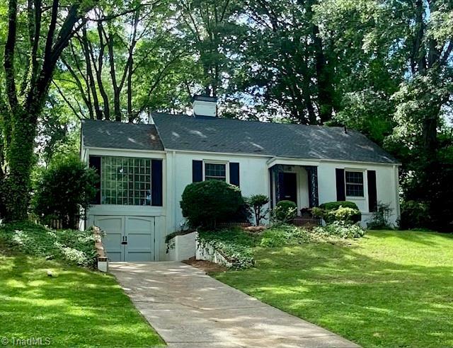 305 W Avondale Dr, Greensboro, NC 27403 - view of front of property featuring driveway, an attached garage, a front lawn, and a chimney